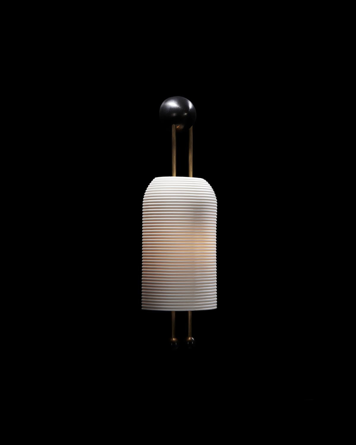 Minimalist wall sconce lantern with ribbed white cylindrical shade and black spherical accents against a black background