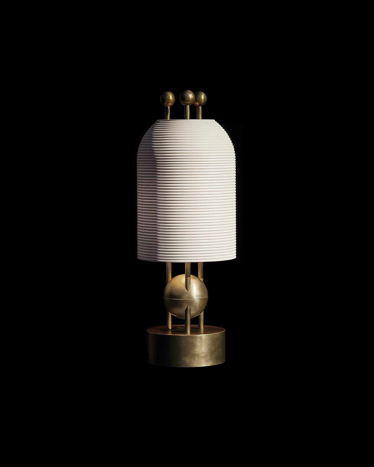 Modern table lamp with ribbed white cylindrical shade and brass geometric base on black background