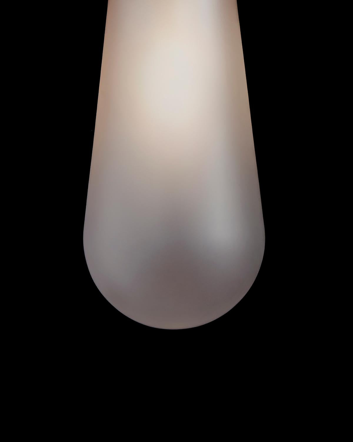 Close-up of a frosted glass pendant light with soft gradient shading against a black background