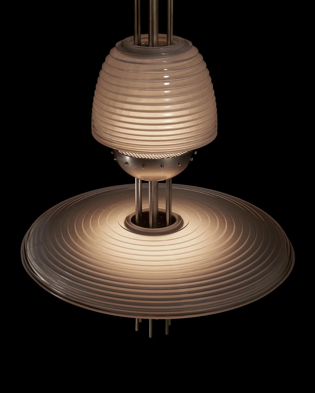 Close-up of a modern pendant light fixture with layered ribbed glass and metal elements against a black background