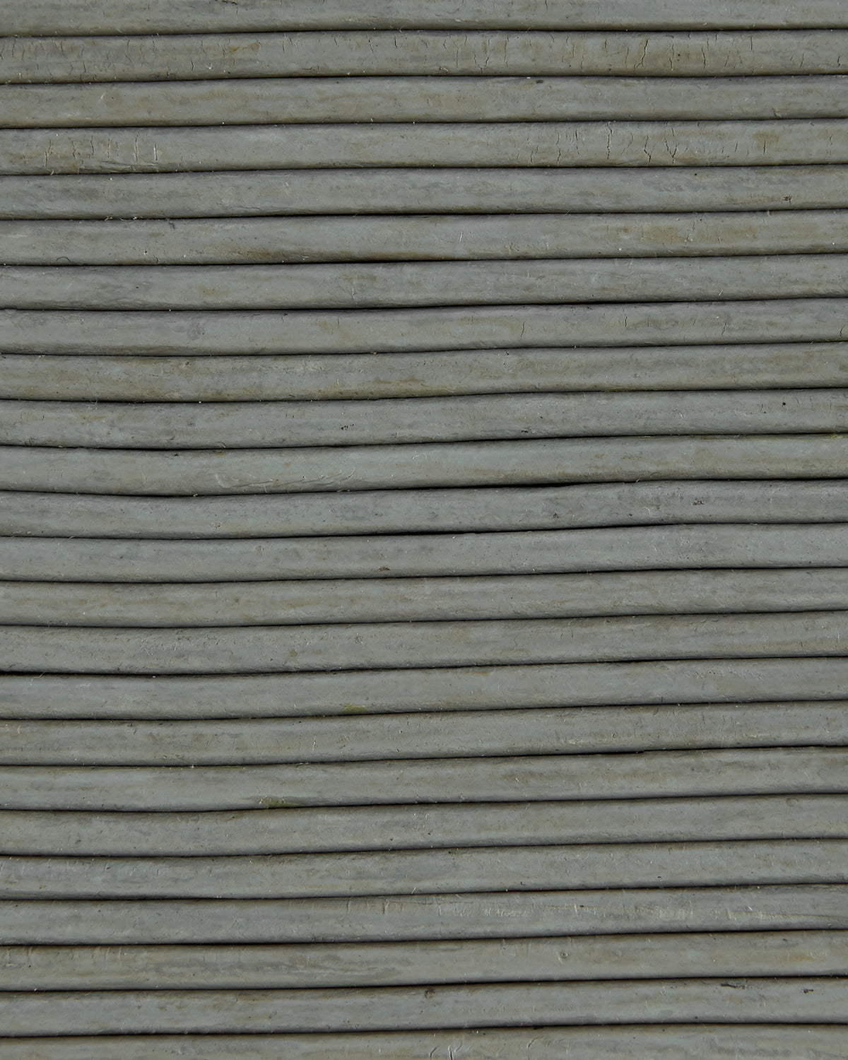 Close-up of tightly arranged horizontal light gray concrete rods with a rough textured surface.