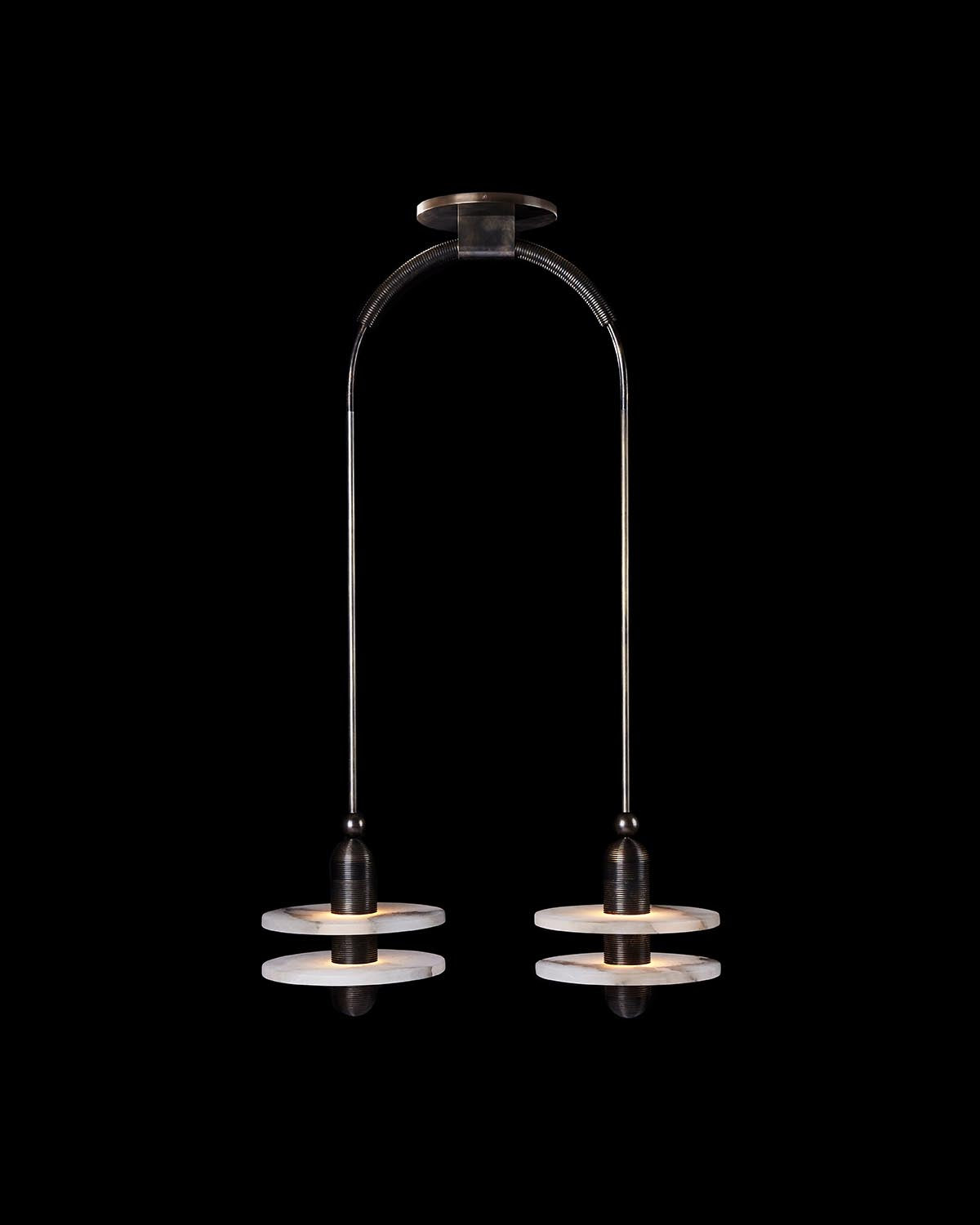Double pendant light with dark metal fixtures and stacked circular shades suspended from ceiling mount on black background