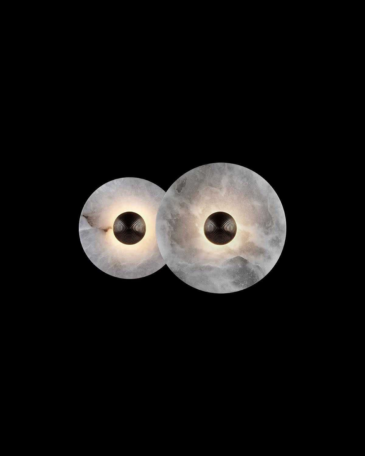 Two overlapping circular white marble light fixtures with textured black center spheres on a black background