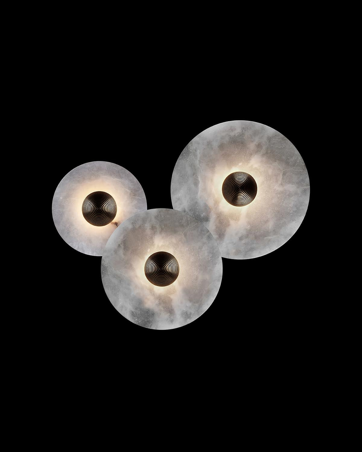 Three circular light fixtures with textured translucent surfaces and metallic centers against a black background