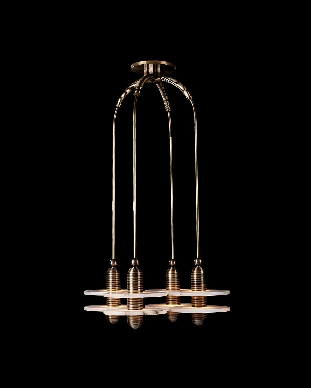 Suspended four-pendant light fixture with brass finish and circular diffusers, set against a black background