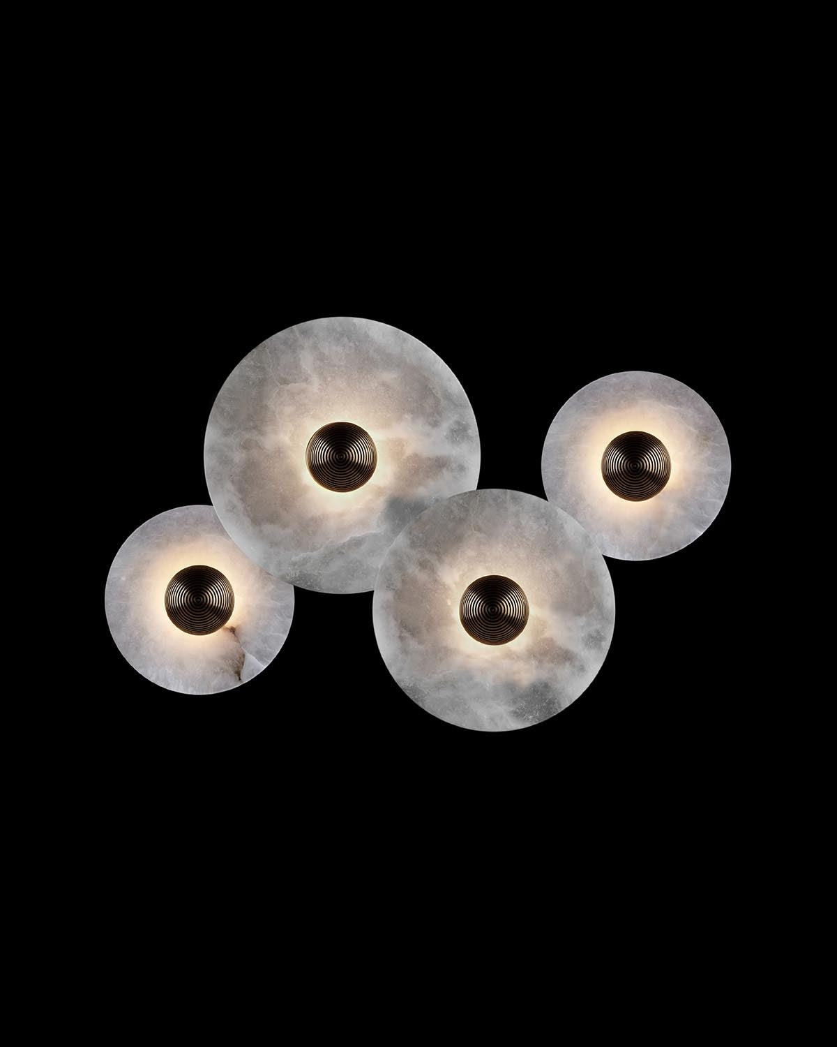 Cluster of four round frosted glass light fixtures with dark central diffusers against a black background