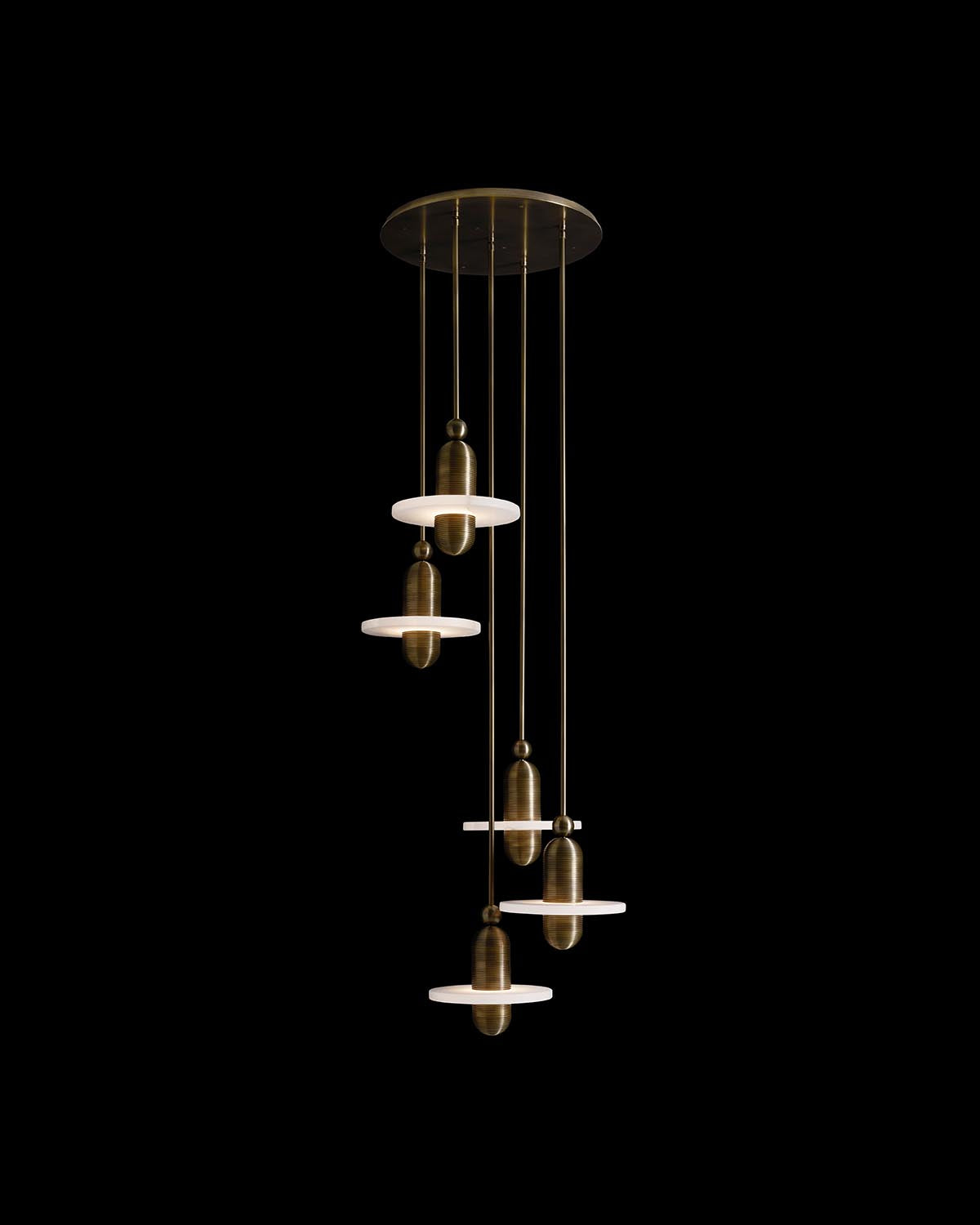 Suspended multi-light installation with four bronze cylindrical pendants and white circular discs against a black background