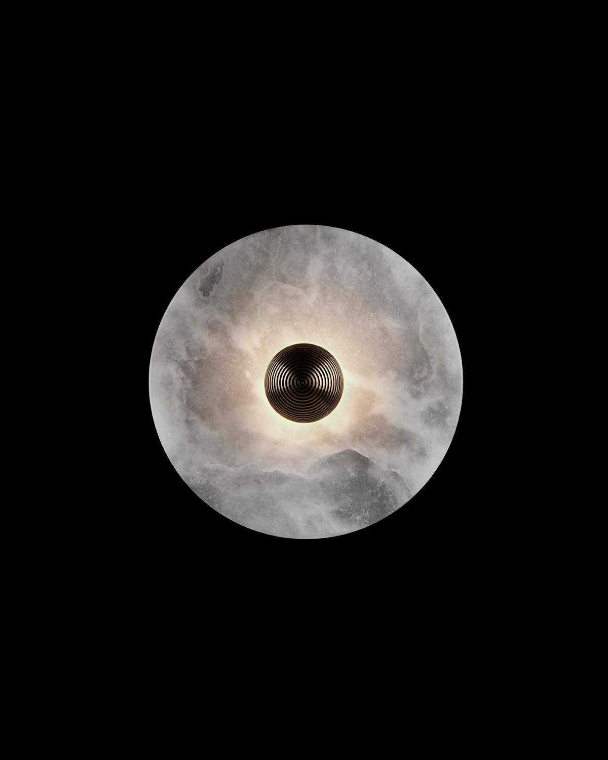 Top-down view of a round alabaster wall sconce with a dark, textured circular center glowing softly against a black background