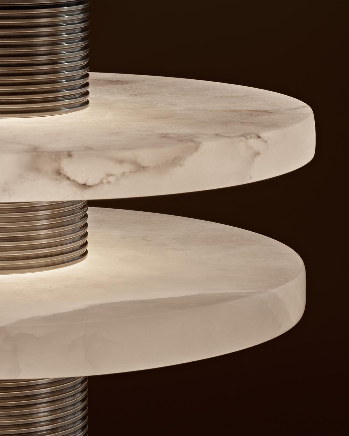 Close-up of illuminated round alabaster stone lamp shades with textured metal cylindrical supports against a dark background