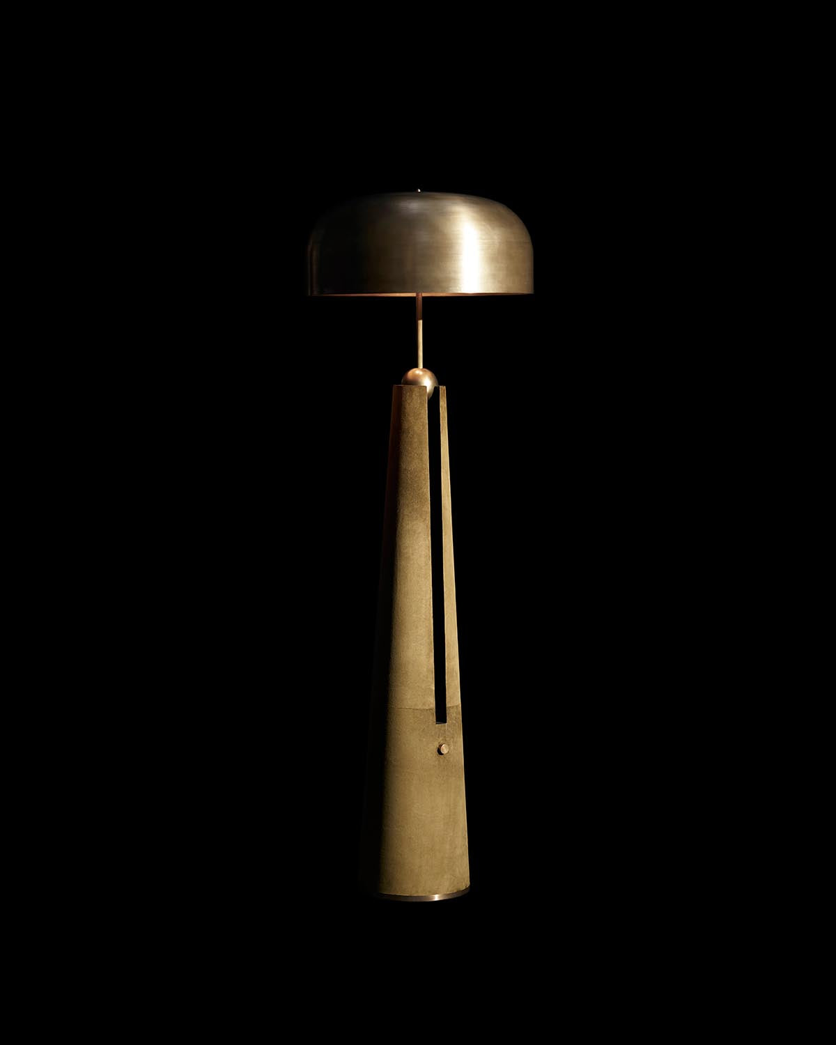 Minimalist floor lamp with a tall tapered base and a rounded top shade in brushed metallic finish against black background