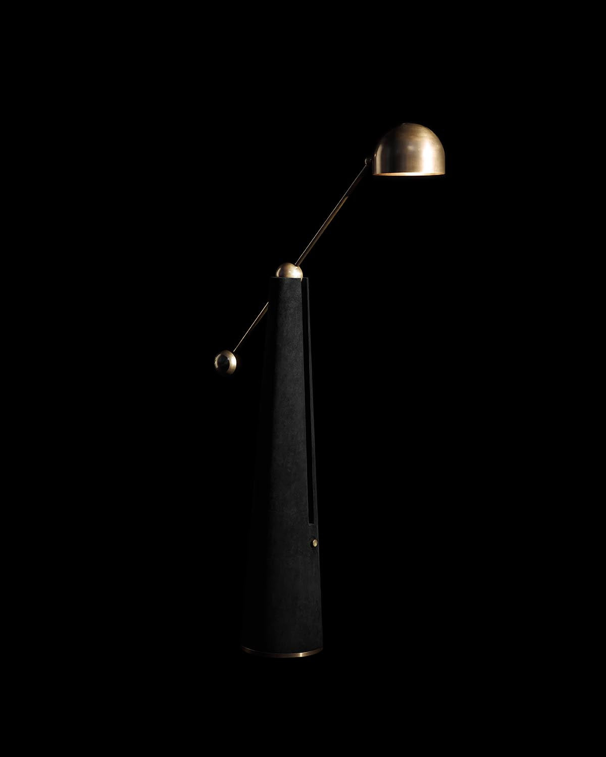 Tall modern reading lamp with black tapered base and brass dome-shaped adjustable shade on black background