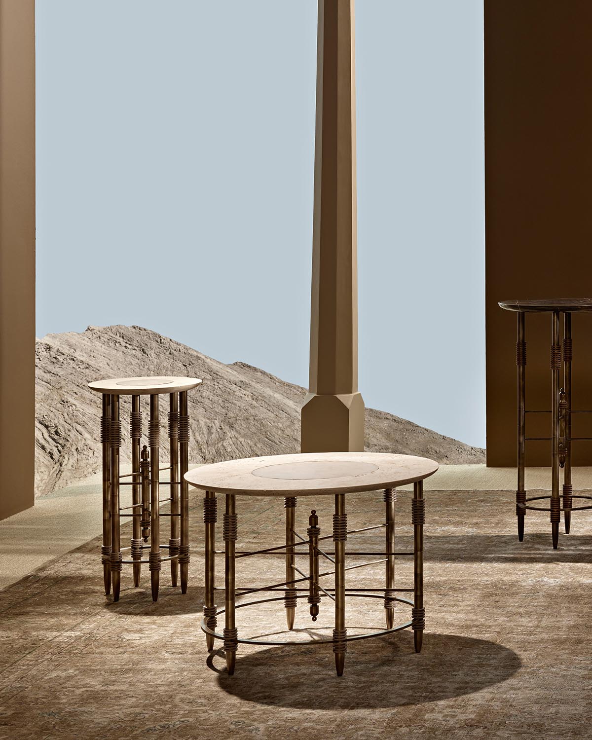 Three round side tables with light stone tops and dark metal turned legs arranged in an architectural setting