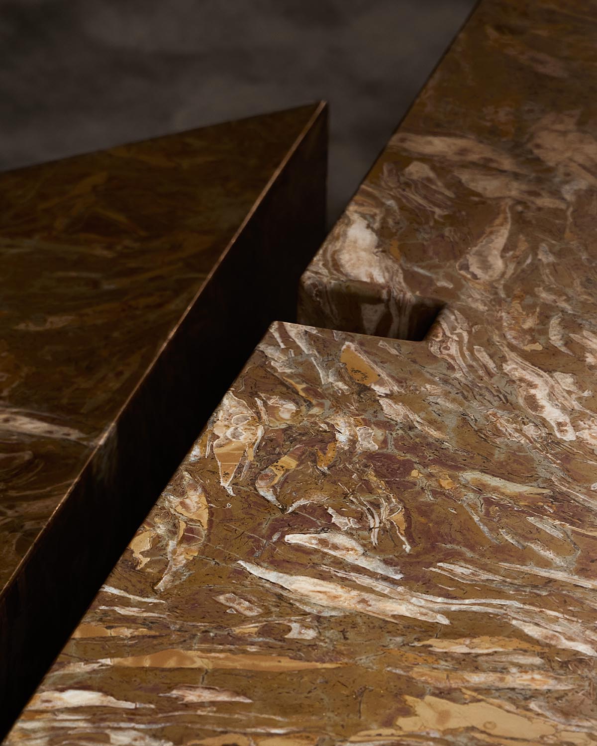 Close-up of a brown marbled stone coffee table with an irregular groove detail on a dark background