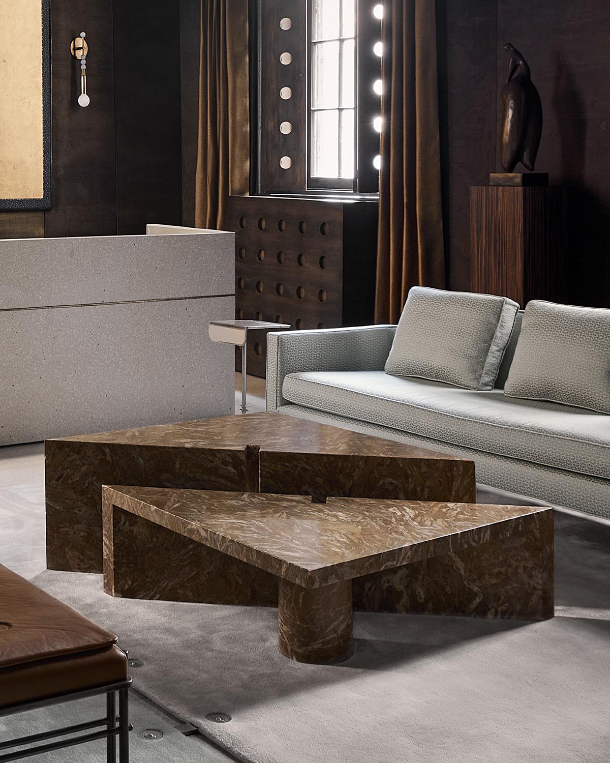 Set of three geometric dark brown marble coffee tables with triangular and rectangular shapes in a modern living room setting