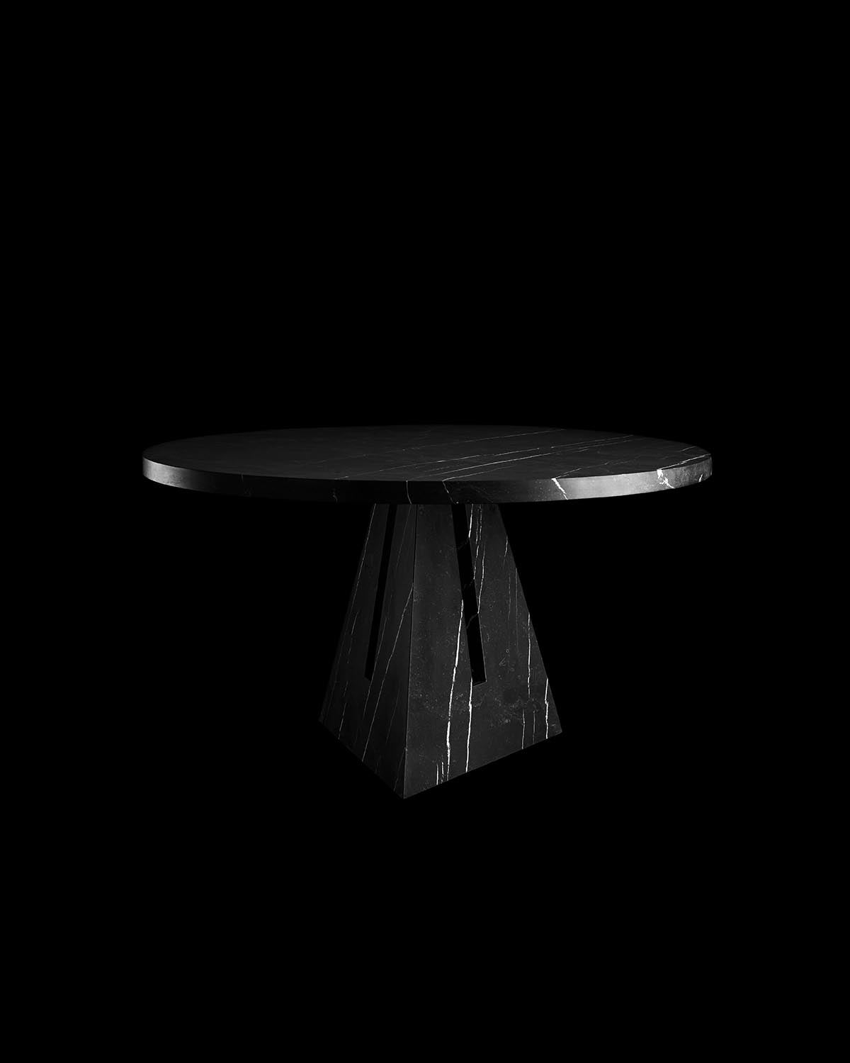 Round black marble dining table with geometric pedestal base and natural white veining on black background