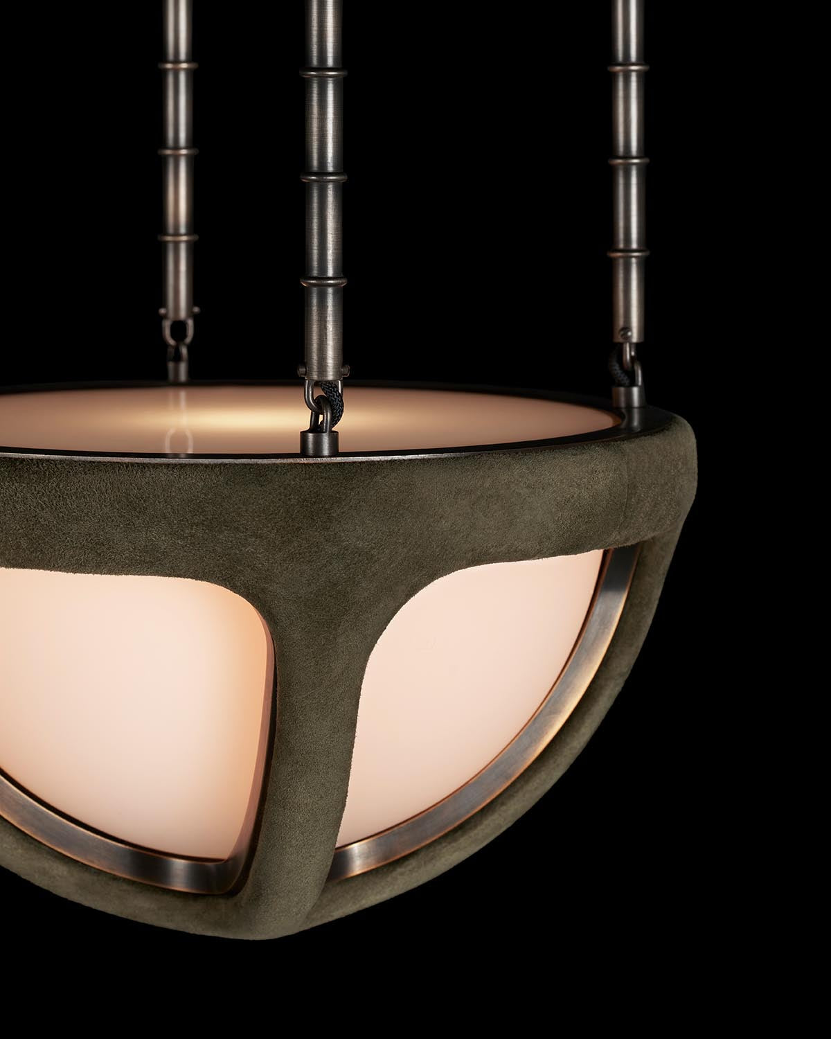 Close-up of a suspended ceiling light with a matte bronze frame and frosted glass diffuser against black background