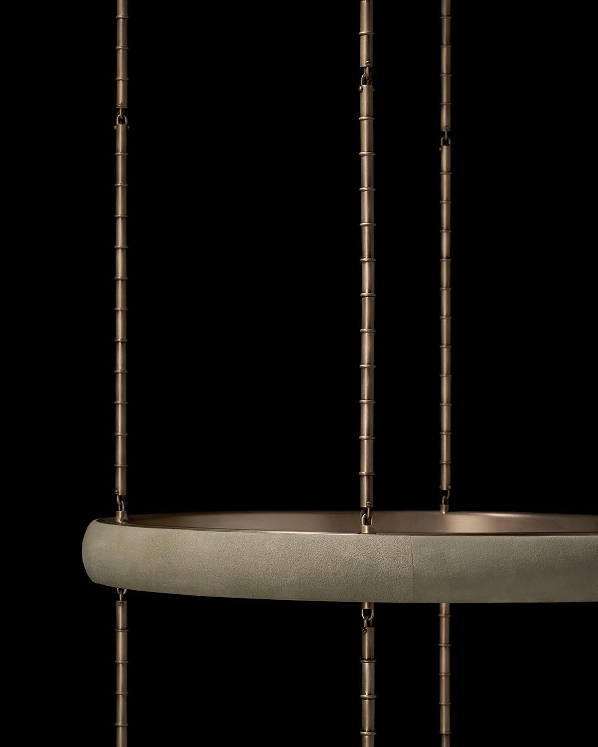 Close-up of a round suspended pendant light with a textured matte finish and metal rods against a black background