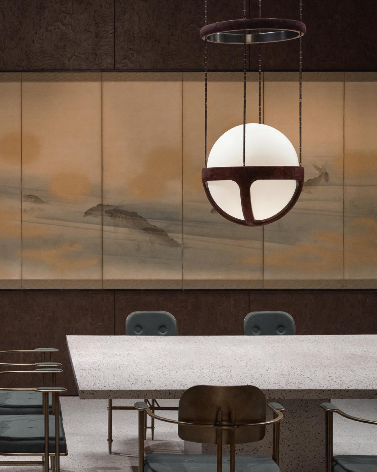 Modern spherical pendant light with dark metal frame hanging above terrazzo dining table and minimalist chairs