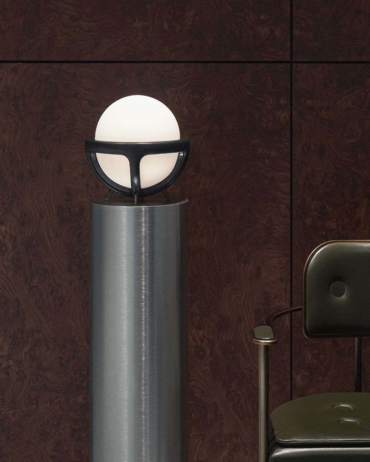 Modern table lamp with glowing spherical white shade held by black semicircular frame on brushed metal pedestal