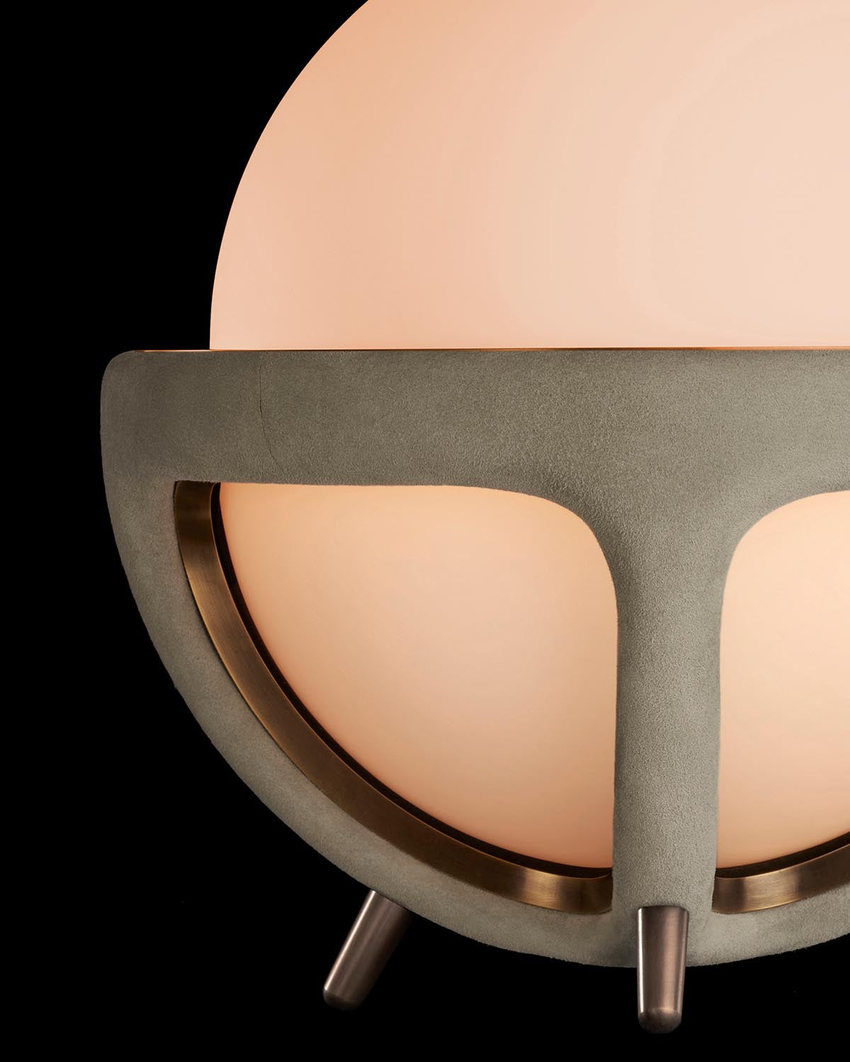 Close-up of a spherical table lamp with a smooth frosted glass globe and matte textured base on black background