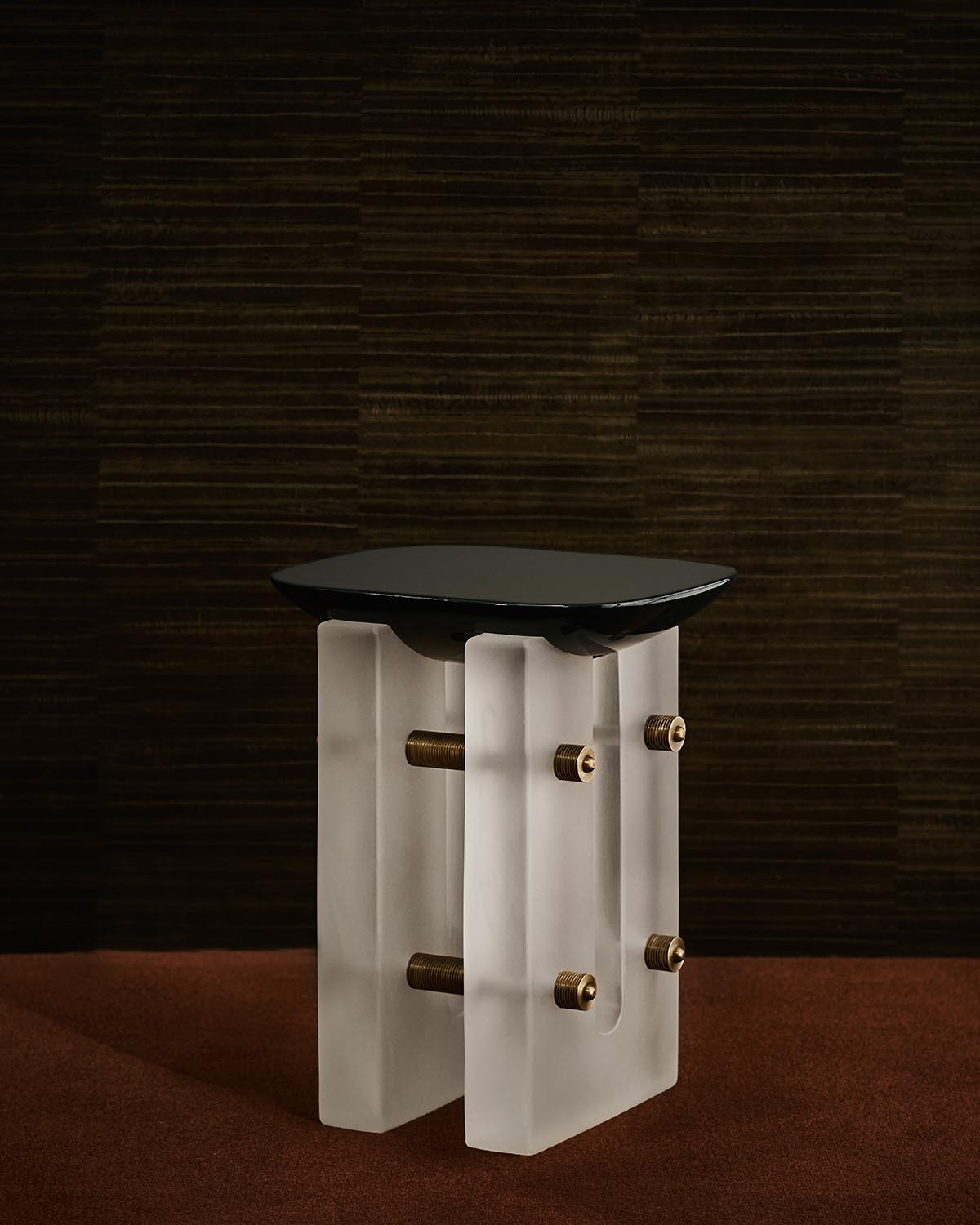Modern cocktail table with a black top supported by translucent rectangular legs and exposed brass connectors