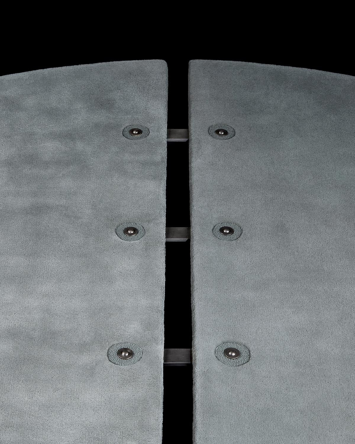 Close-up of textured gray panels with circular metal fasteners and black connecting bars on a black background