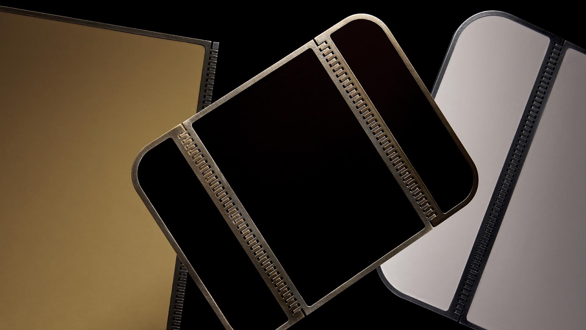 Close-up of three empty photo album pages in gold, black, and white with black spiral binding on a black background