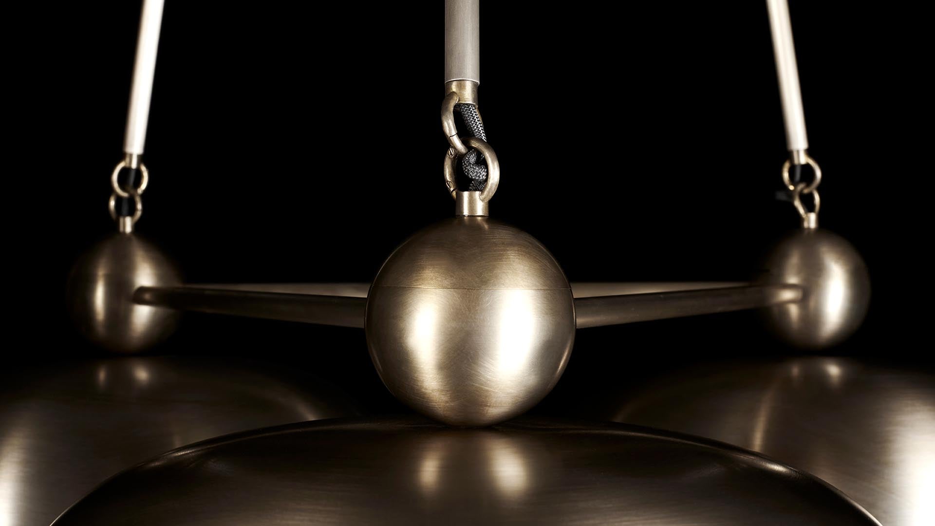 Close-up of a metallic balance scale with three spheres connected by rods against a dark background
