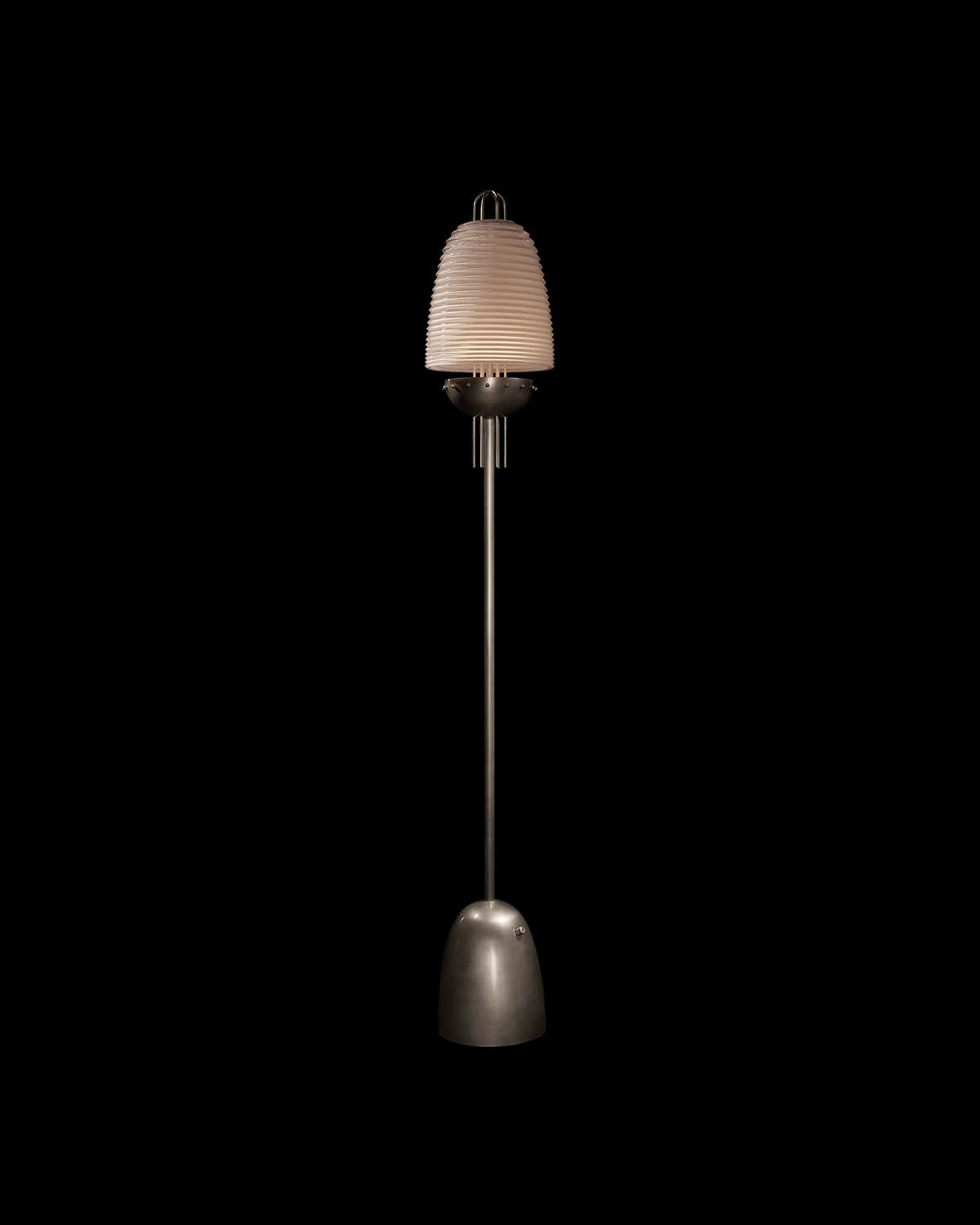 Tall floor lamp with ribbed beige glass shade and slender metal base against a black background