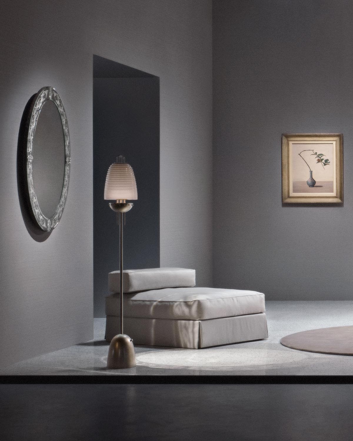 Minimalist room with SIGNAL X floor lamp next to a low beige cushioned seat, round mirror, and framed artwork on gray walls