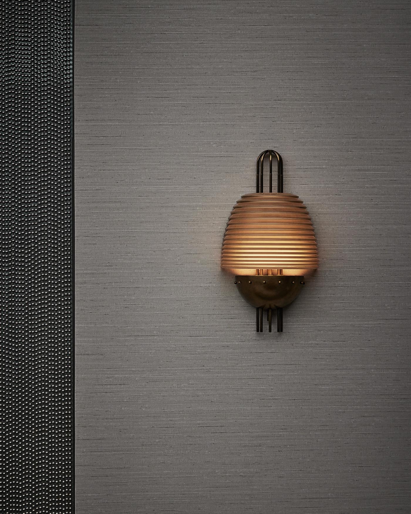 Wall-mounted sconce with ribbed amber glass shade and antique brass base against textured gray wall