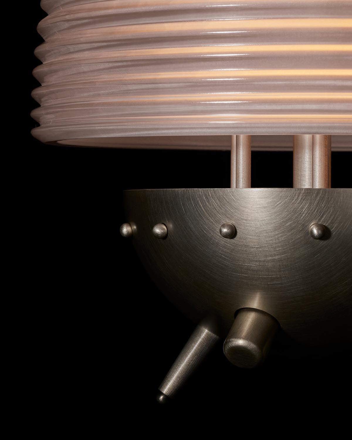 Close-up of SIGNAL X table lamp showing ribbed translucent shade and brushed metal base with rivet details on black background