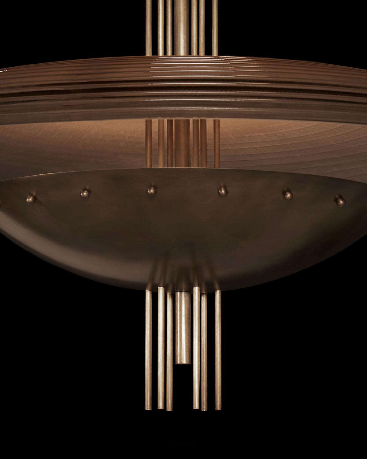Close-up of a bronze-toned ceiling light fixture with ribbed circular frame and vertical metal rods against black background