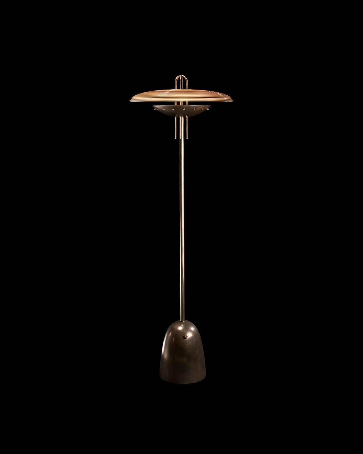 Tall floor lamp with slender metal stand and wide circular shade with horizontal grooves on black background