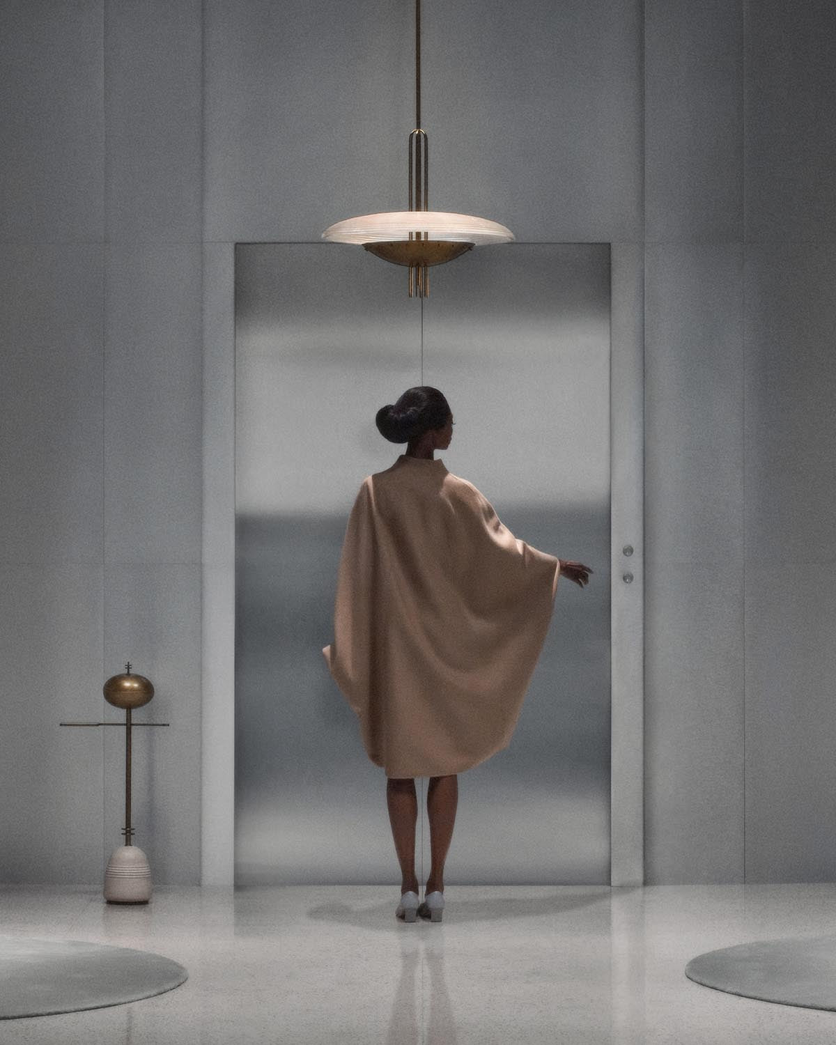 Modern pendant light with circular translucent shade hanging above a woman in a minimalist grey room with sculptural decor
