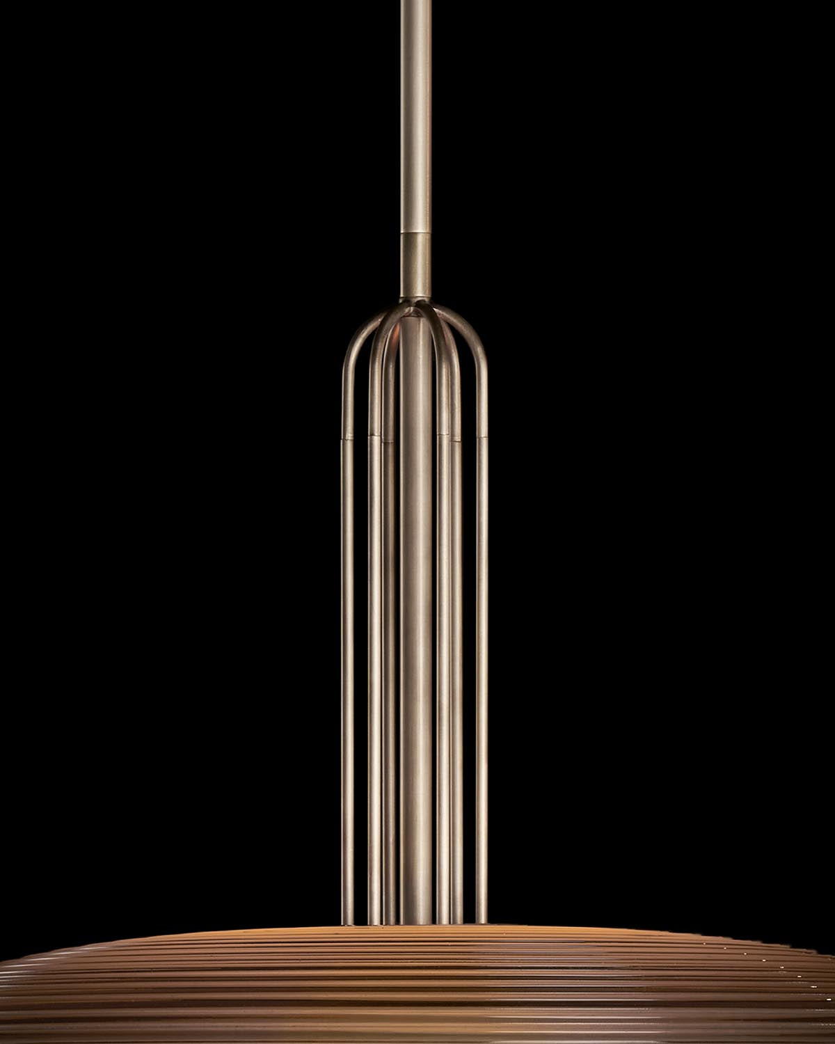 Close-up of a metallic pendant light with vertical tubular rods extending from a circular wooden slatted shade against black background