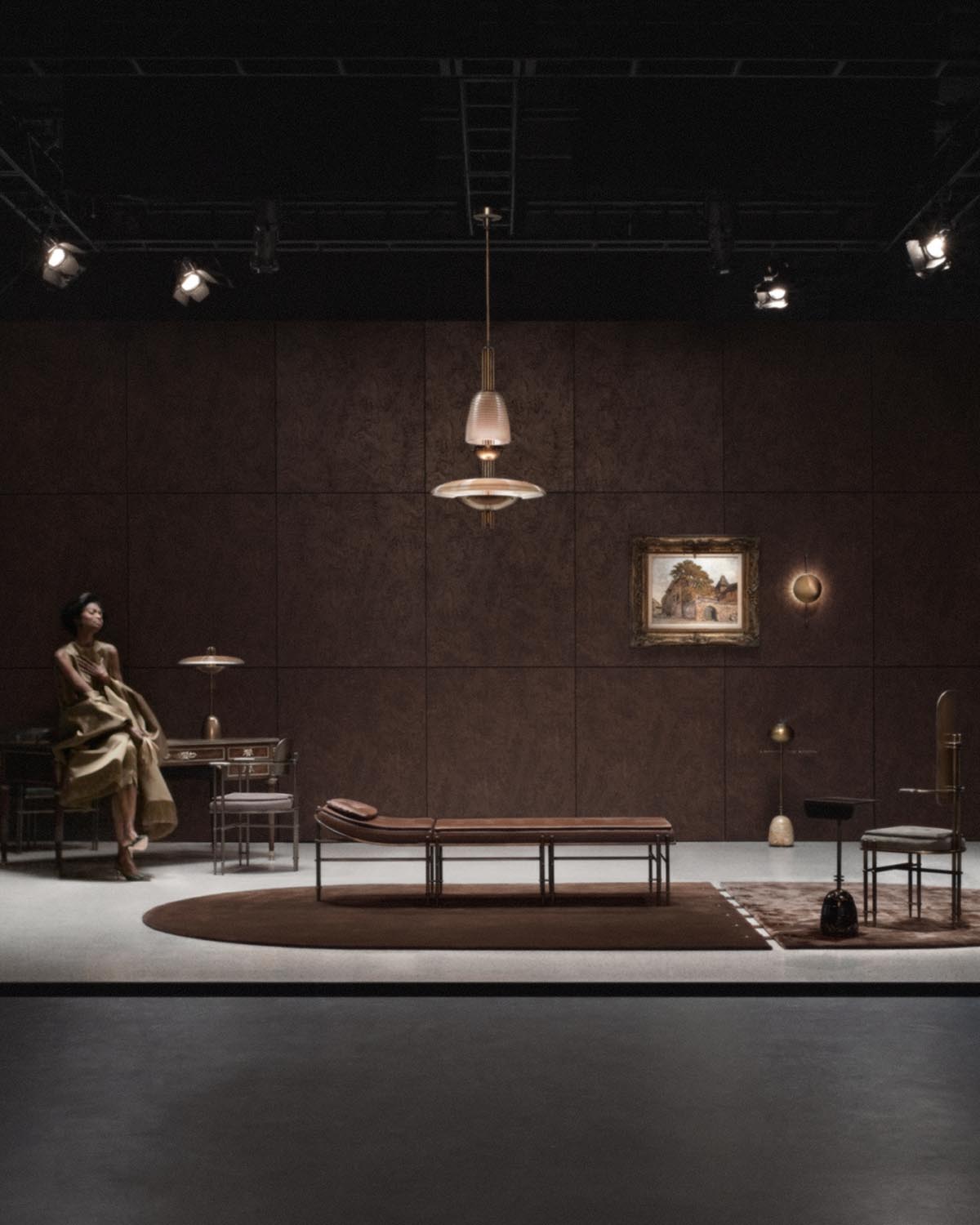 Modern pendant light with frosted glass and brass details hanging over minimalist seating area in dark, elegant room