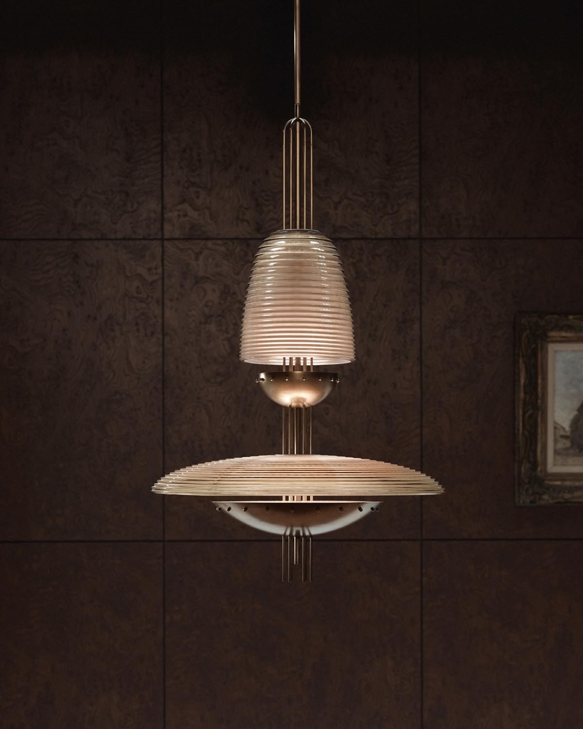Modern pendant light with layered ribbed glass shade and brass details against a dark wood paneled wall