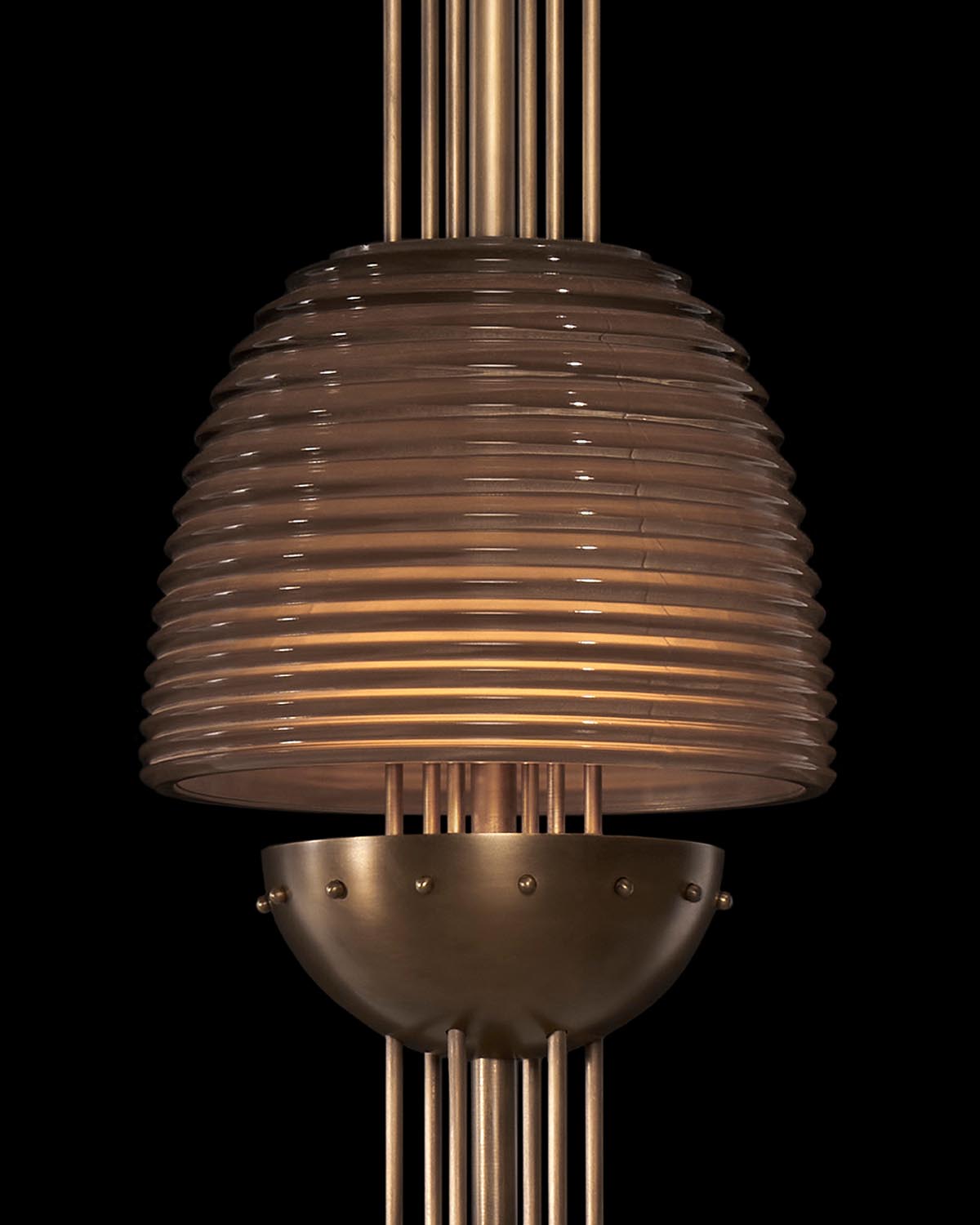 Close-up of SIGNAL Z pendant light with ribbed glass shade and brass metal detailing against black background