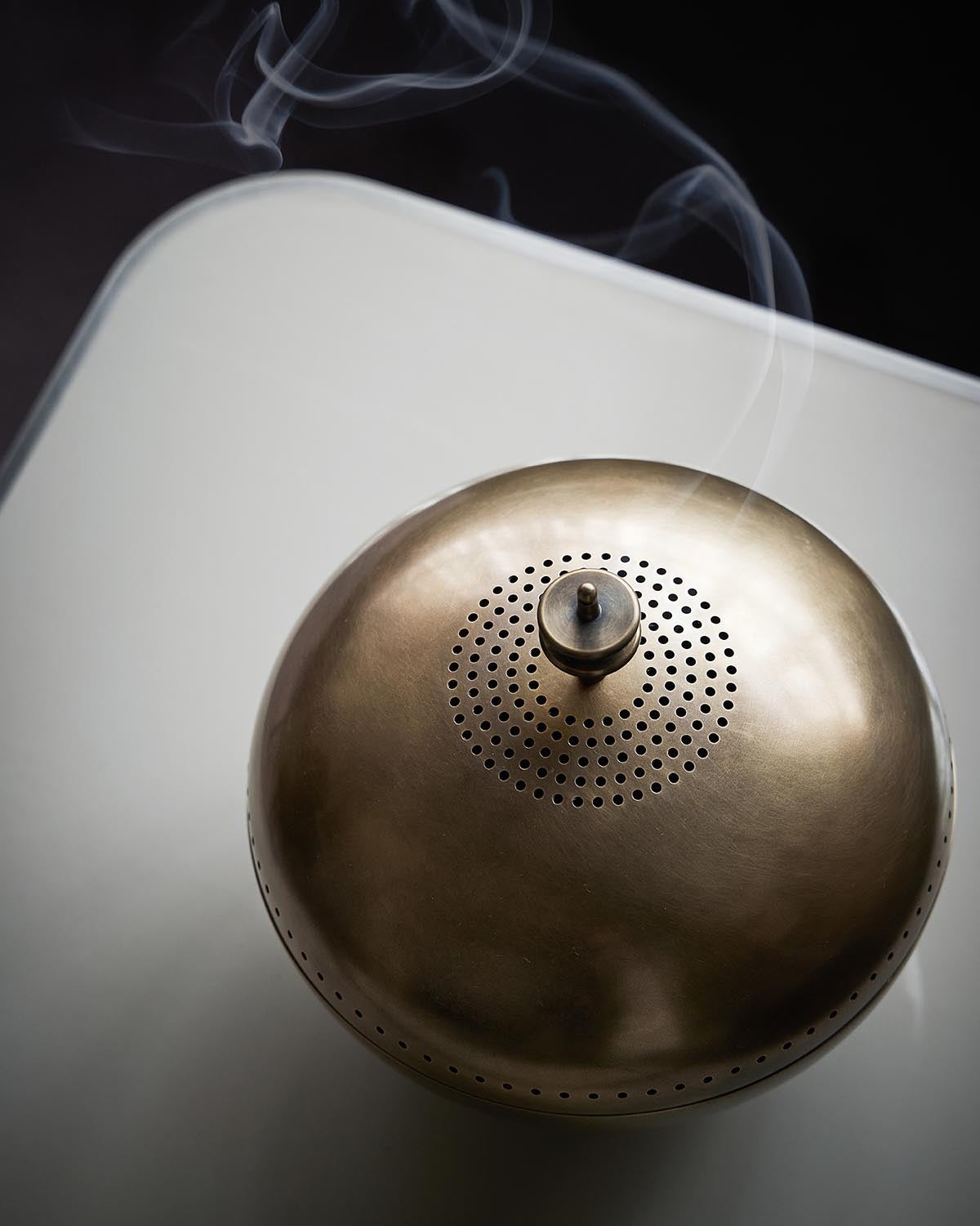 Birds eye view of a brass vessel on a gray table top.