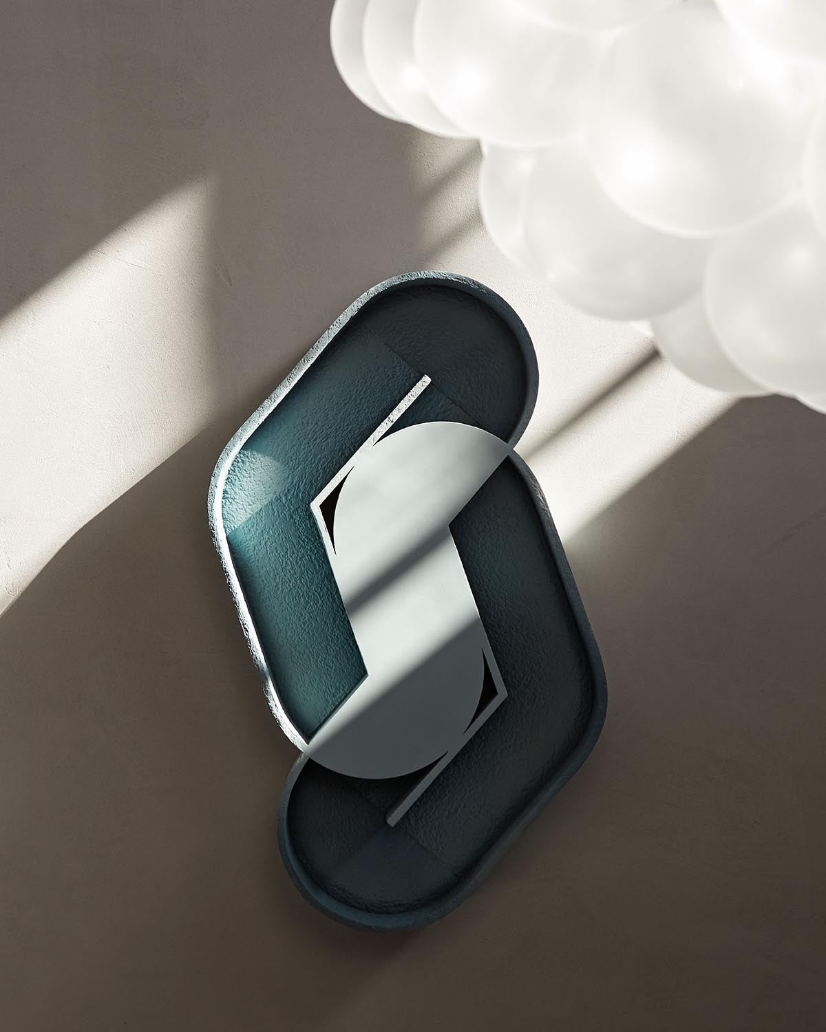 Top-down view of two overlapping textured trays in muted blue and gray tones with soft shadows on a neutral surface