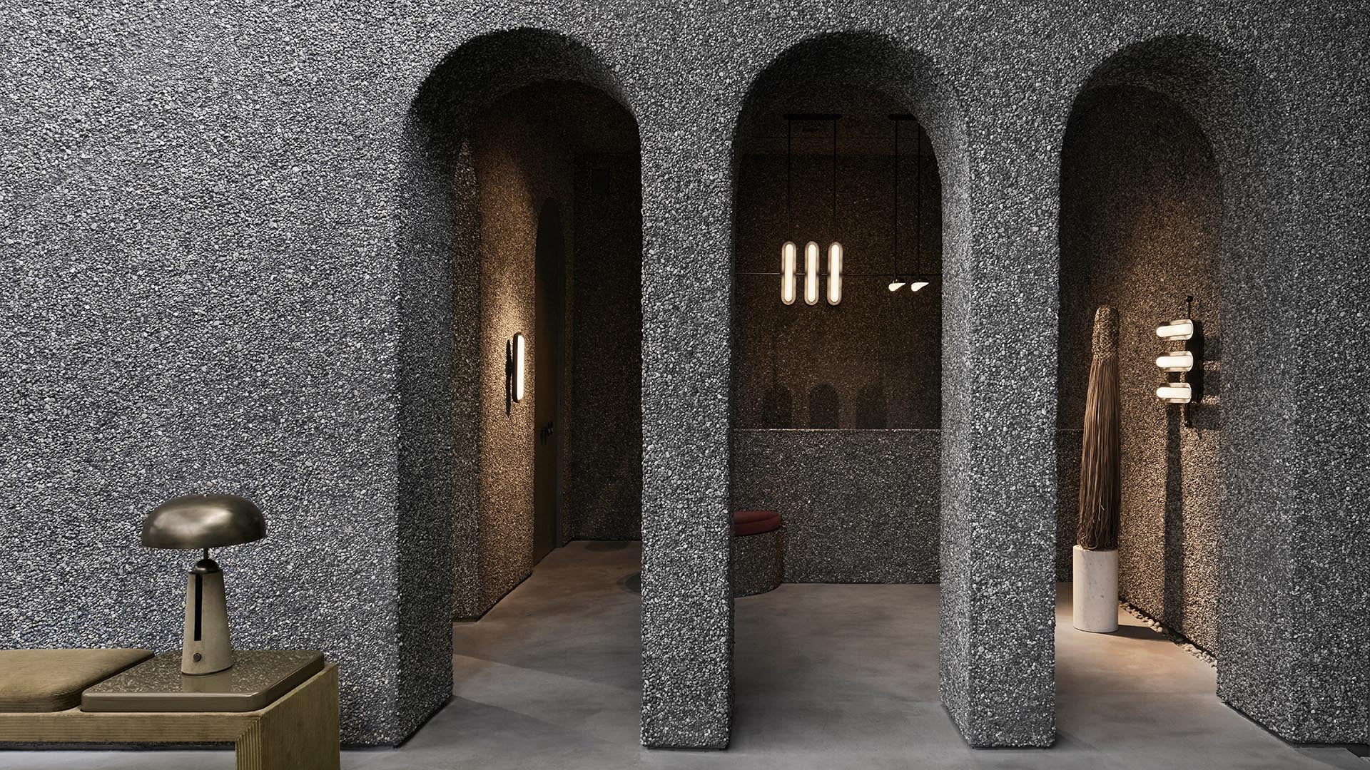 Interior space with textured grey arched walls, concrete floor, minimalist lighting, and modern decor elements
