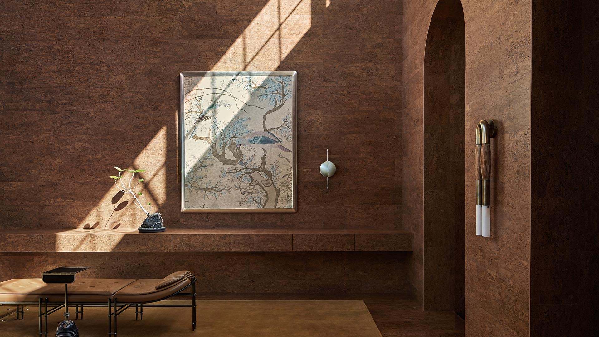 Minimalist interior with textured brown walls, arched doorway, abstract wall art, and leather chaise lounge in natural light