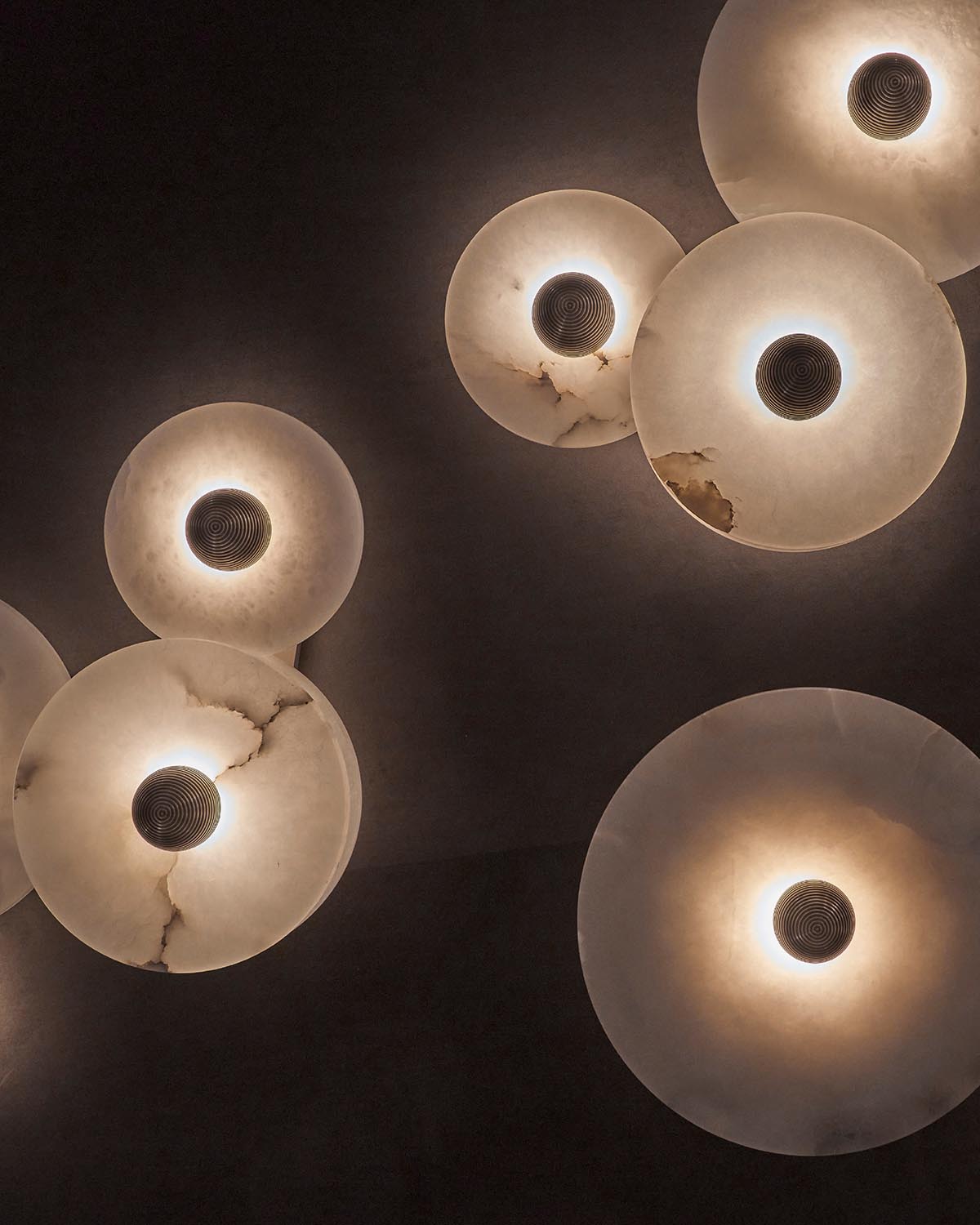Overhead view of round ceiling lights with translucent, marbled shades and dark central fixtures on a dark background