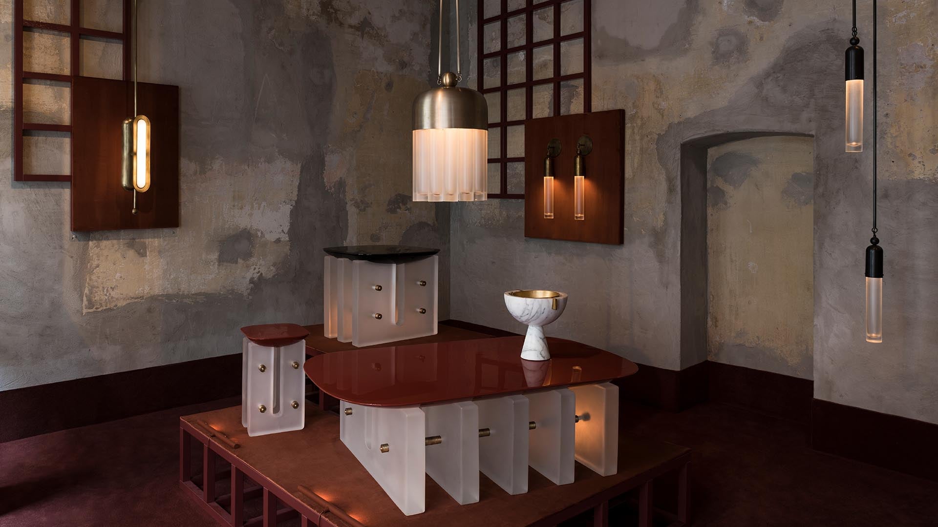 Interior with rustic textured walls, pendant lights, and modern sculptural furniture in warm brown and beige tones.