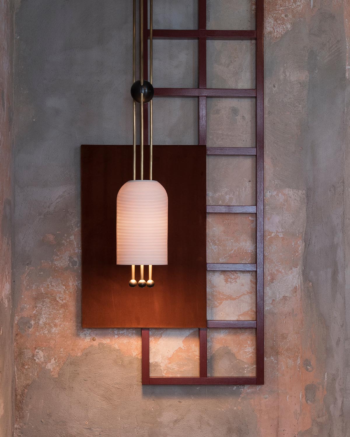 Modern pendant light with frosted ribbed glass shade mounted on rustic textured wall with dark geometric frame panel.