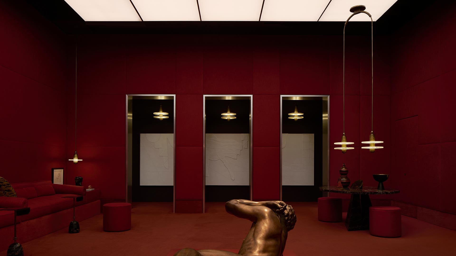 Dark red room with three large rectangular mirrors, hanging pendant lights, and bronze sculpture in foreground.