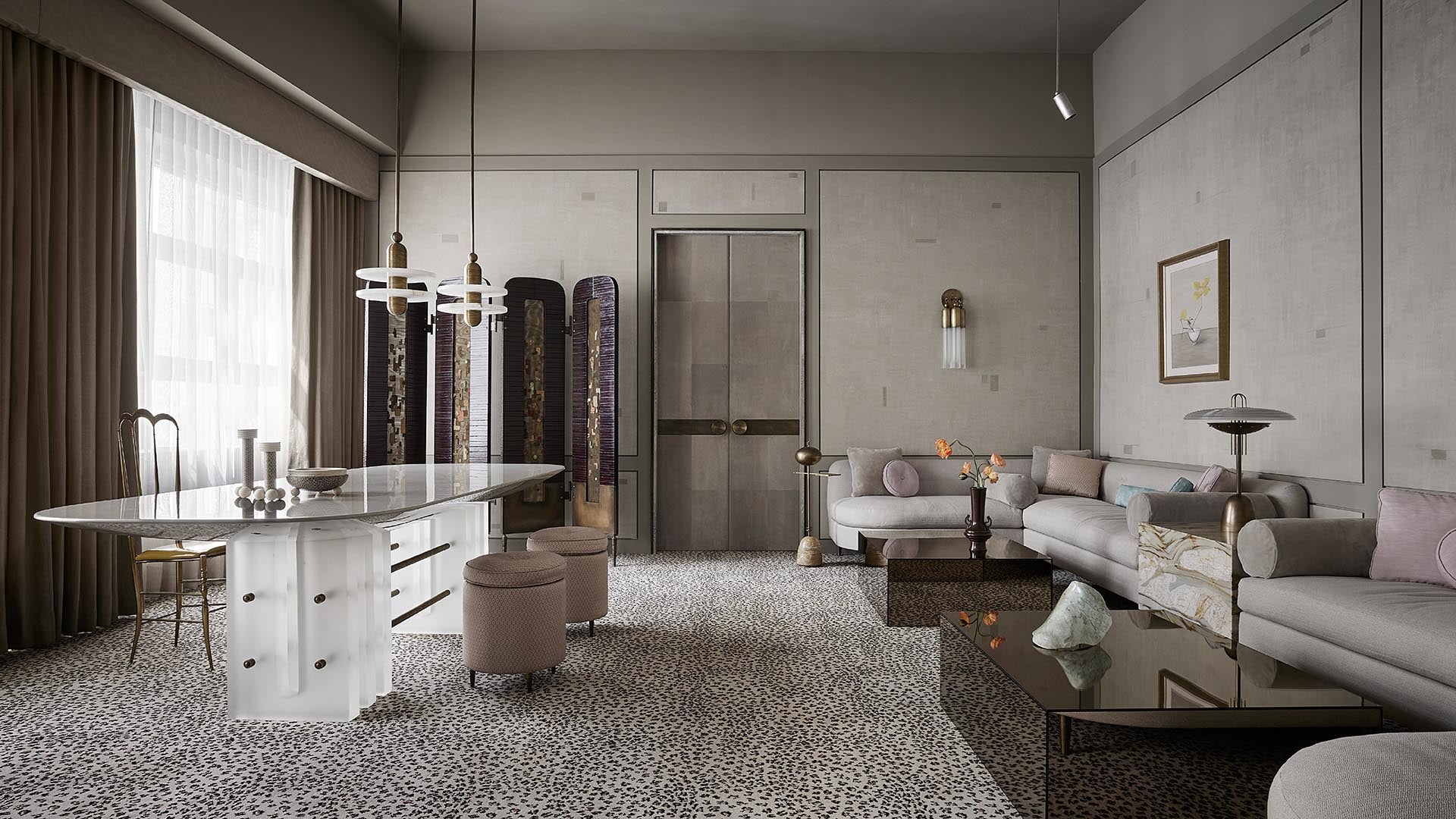 Spacious modern living room with light gray sectional sofa, marble dining table, patterned carpet, and muted wall decor