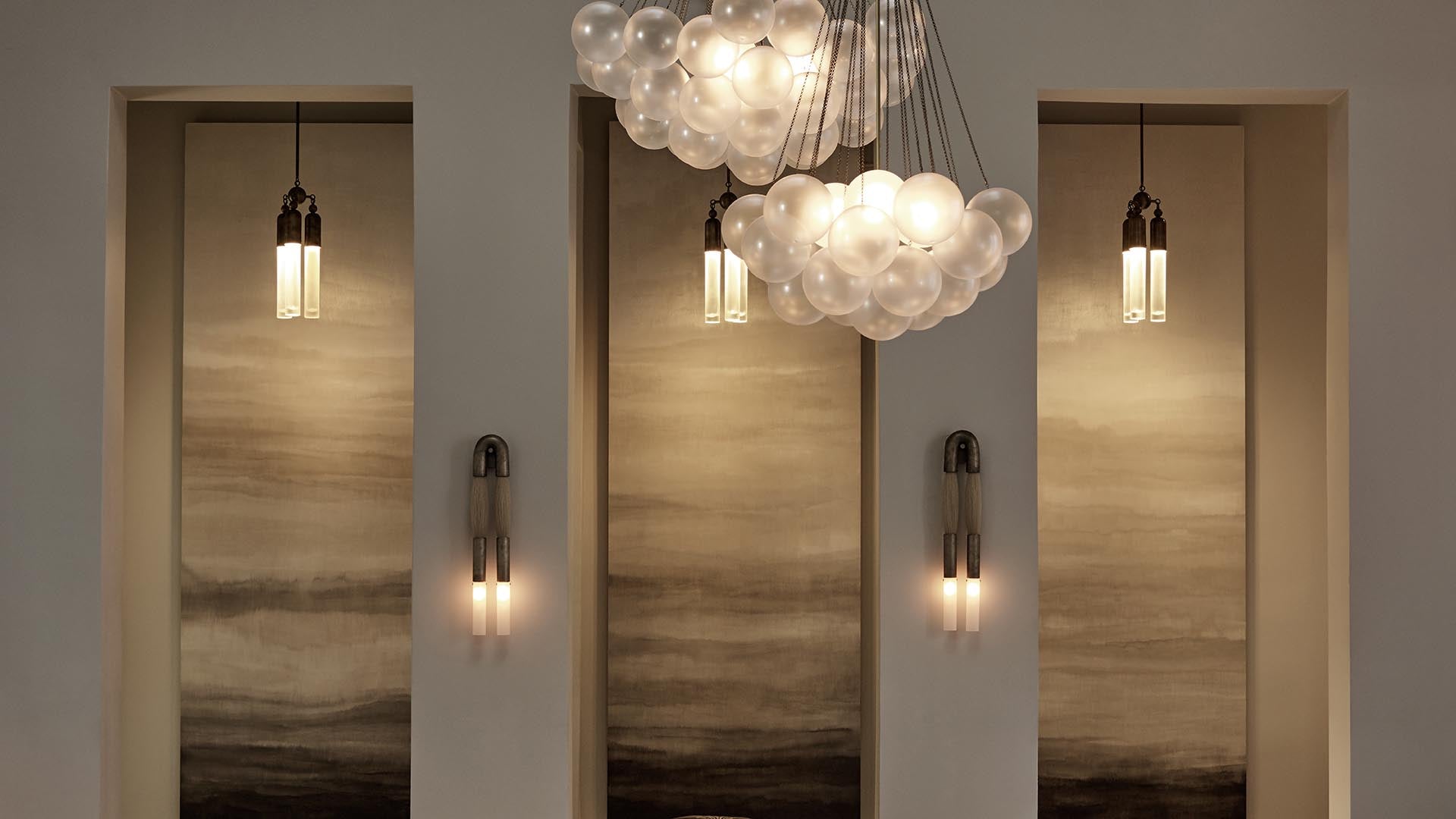 Modern interior wall with three recessed niches featuring vertical pendant lights and a cluster of round glass globe ceiling lamps