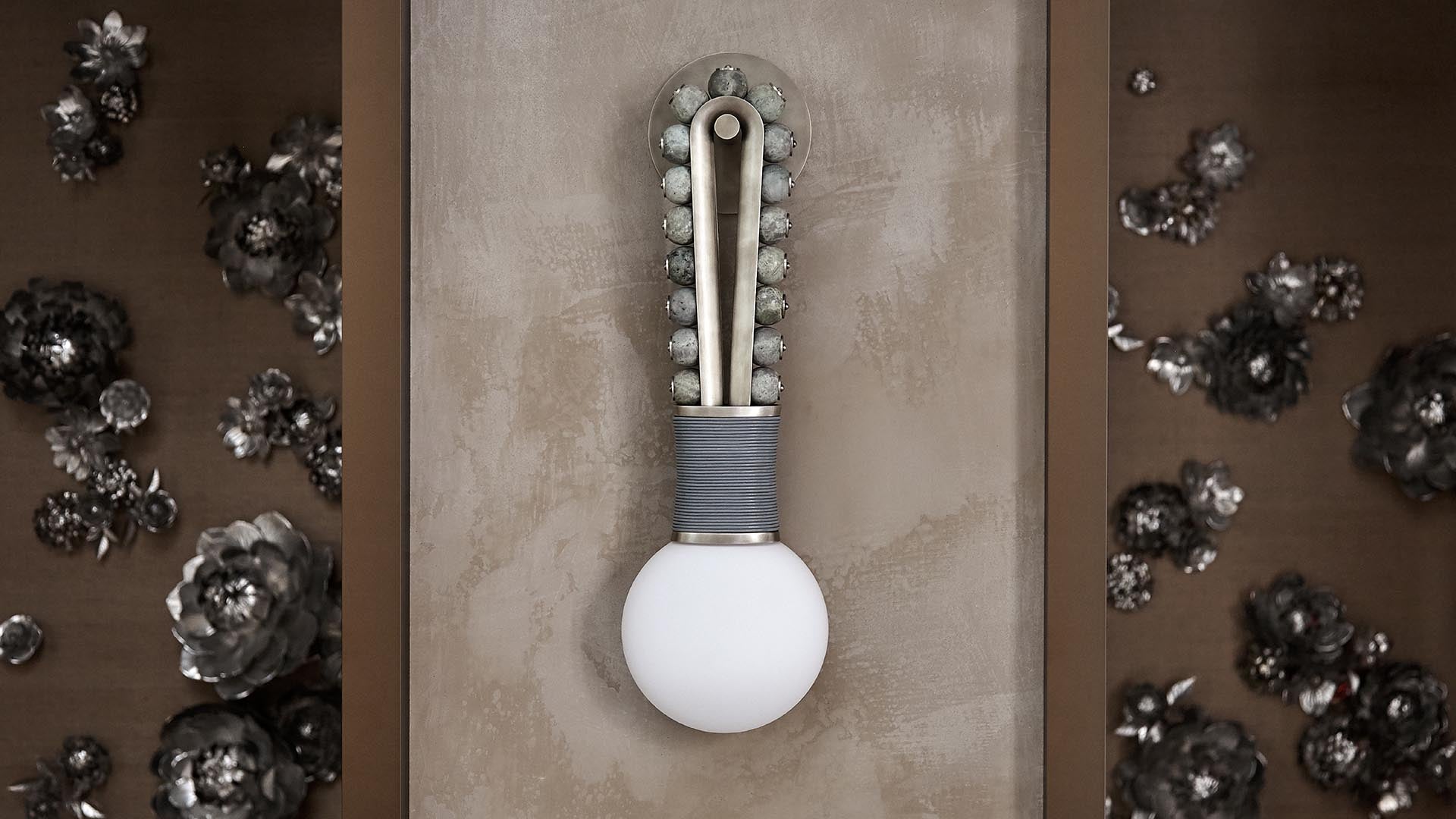 Decorative wall sconce with a white bulb and looped metal design mounted on a textured taupe wall panel